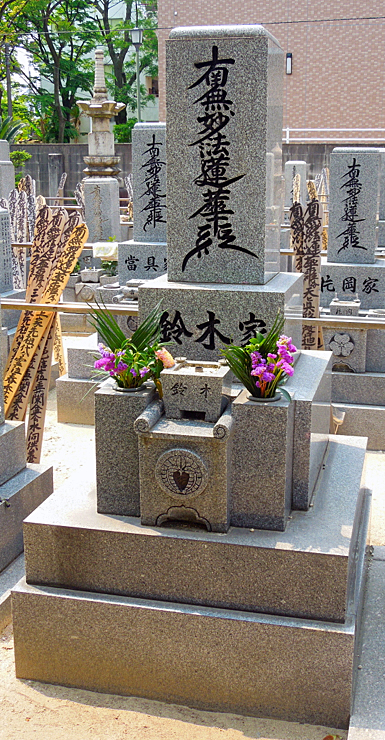 竿石の正面に「南無妙法蓮華経」のお題目を刻んだ墓石の例。左右の墓にも題目が刻まれ、木製の卒塔婆が立てられています